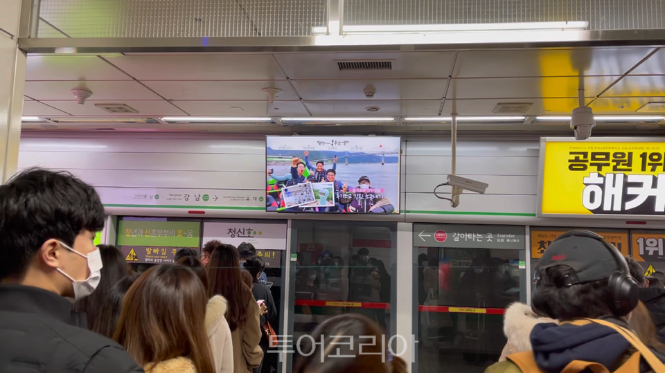 서울 강남역에서 『강진에서 일주일 살기』홍보 영상을 지하철 승객들이 시청하고 있다